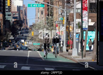 200322 -- NEW YORK, le 22 mars 2020 -- des personnes portant un masque facial font du vélo sur la 2nd Avenue à New York, aux États-Unis, le 21 mars 2020. Le gouverneur de l’État américain de New York Andrew Cuomo a déclaré samedi qu’un total de 10 356 personnes dans l’État avaient été testées positives au nouveau coronavirus, soit un saut de 3 254 par rapport à la veille. Vendredi, Cuomo a annoncé qu’un mandat, qui oblige les personnes travaillant dans des entreprises non essentielles à rester à la maison, entrera en vigueur dimanche soir. U.S.-NEW YORK-COVID-19-MANDATE WangxYing PUBLICATIONxNOTxINxCHN Banque D'Images