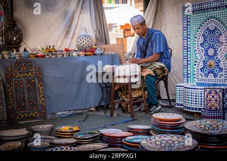 Atelier artisanal marocain, avec ouvrier en arrière-plan, entouré de leurs produits. Photographie prise le 2 septembre 2023 dans la ville d'AV Banque D'Images