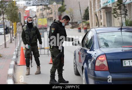 200323 -- HÉBRON, le 23 mars 2020 -- Un policier palestinien travaille à un poste de contrôle à l'entrée de la ville d'Hébron en Cisjordanie, le 23 mars 2020. Les autorités palestiniennes ont déclaré dimanche un confinement de 14 jours en Cisjordanie dans le cadre des mesures visant à lutter contre la propagation de la pandémie de coronavirus. Le Premier ministre Mohammed Ishtaye a annoncé une interdiction des transports et des déplacements entre les districts de Cisjordanie, exhortant les citoyens à rester chez eux. Photo de Mamoun Wazwaz/Xinhua MIDEAST-HEBRON-COVID-19-MEASURES XiongxSihao PUBLICATIONxNOTxINxCHN Banque D'Images