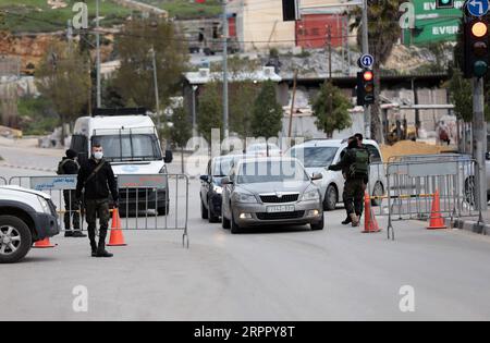 200323 -- HÉBRON, le 23 mars 2020 -- Un policier palestinien parle à un chauffeur à un poste de contrôle à l'entrée de la ville de Hébron en Cisjordanie, le 23 mars 2020. Les autorités palestiniennes ont déclaré dimanche un confinement de 14 jours en Cisjordanie dans le cadre des mesures visant à lutter contre la propagation de la pandémie de coronavirus. Le Premier ministre Mohammed Ishtaye a annoncé une interdiction des transports et des déplacements entre les districts de Cisjordanie, exhortant les citoyens à rester chez eux. Photo de Mamoun Wazwaz/Xinhua MIDEAST-HEBRON-COVID-19-MEASURES XiongxSihao PUBLICATIONxNOTxINxCHN Banque D'Images