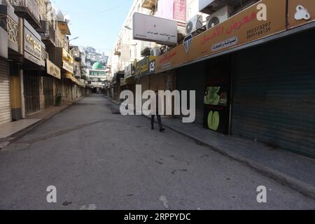 200323 -- NAPLOUSE, le 23 mars 2020 -- Un palestinien passe devant des magasins fermés dans une rue vide de la ville de Naplouse, en Cisjordanie, le 23 mars 2020. Les autorités palestiniennes ont déclaré dimanche un confinement de 14 jours en Cisjordanie dans le cadre des mesures visant à lutter contre la propagation de la pandémie de coronavirus. Le Premier ministre Mohammed Ishtaye a annoncé une interdiction des transports et des déplacements entre les districts de Cisjordanie, exhortant les citoyens à rester chez eux. Photo de Nidal Eshtayeh/Xinhua MIDEAST-NAPLOUSE-COVID-19-MESURES XiongxSihao PUBLICATIONxNOTxINxCHN Banque D'Images