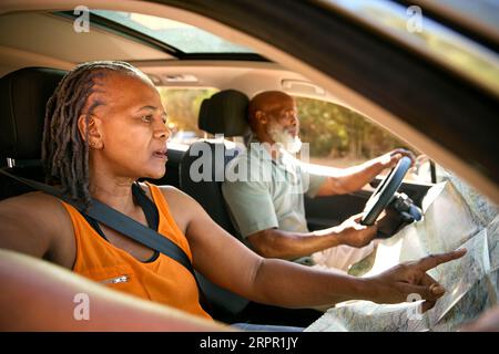 Couple senior confus sur une excursion d'une journée conduite en voiture lecture de la carte Looking Lost Banque D'Images