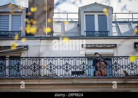 200329 -- PARIS, le 29 mars 2020 Xinhua -- le violoncelliste Camilo Peralta joue du violoncelle sur son balcon à Paris, France, le 28 mars 2020. La France est en confinement pour tenter de contenir la propagation du COVID-19. Photo Aurelien Morissard/Xinhua FRANCE-PARIS-COVID-19-BALCONY-MUSICIAN PUBLICATIONxNOTxINxCHN Banque D'Images