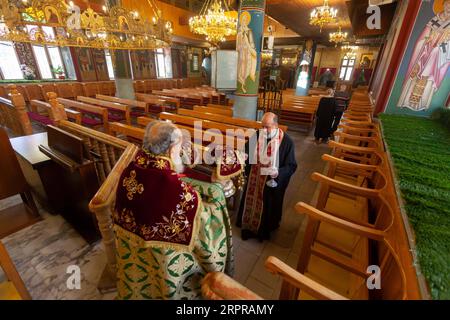 200330 -- BETHLÉEM, le 30 mars 2020 Xinhua -- des prêtres dirigent une messe dimanche vide dans une église orthodoxe de Beit Sahour près de la ville de Bethléem en Cisjordanie le 29 mars 2020. Pour la toute première fois, Raed al-Atrash, un palestinien de 54 ans de Bethléem, en Cisjordanie, a assisté à la messe du dimanche avec sa famille à travers une émission télévisée en direct, alors que les églises sont fermées dans le cadre des précautions contre la propagation du nouveau coronavirus. POUR Y ALLER : les chrétiens en Palestine assistent à des prières en direct alors que les églises ferment sur les craintes du coronavirus photo de Luay Sababa/Xinhua MIDEAST-BETHLEHE Banque D'Images