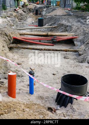 Vue de reconstruction de rue avec tranchée profonde, tuyaux souterrains anciens et remplacés, nouveau puits en plastique vertical Banque D'Images