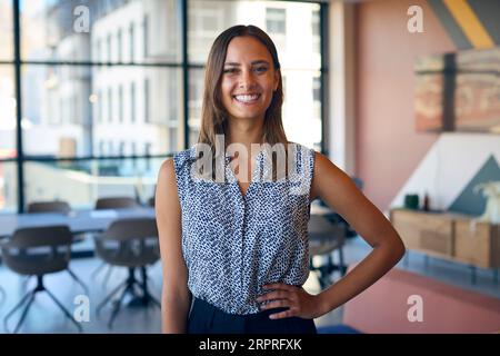 Portrait de jeune femme d'affaires souriante debout dans le bureau vide Banque D'Images