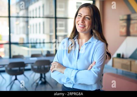 Portrait de souriant mature Businesswoman debout dans le bureau vide Banque D'Images