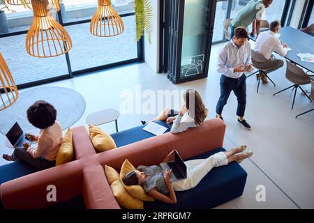 Vue du dessus du bureau moderne ouvert avec le personnel travaillant autour de la table et coin salon Banque D'Images