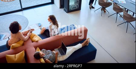 Vue du dessus du bureau moderne ouvert avec personnel féminin travaillant dans le coin salon Banque D'Images