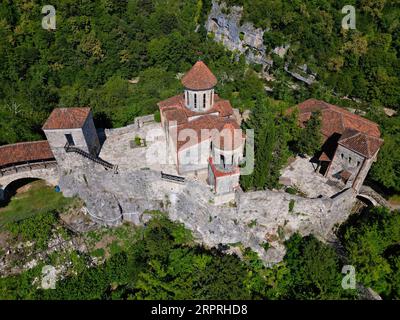 Un château pittoresque avec un toit de tuiles rouges et deux cheminées au sommet de murs en pierre, situé sur une colline surplombant la campagne environnante Banque D'Images