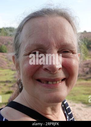 Femme dans sa soixantaine sans maquillage semble heureuse dans l'appareil photo. Une de ses dents est défaillante Banque D'Images