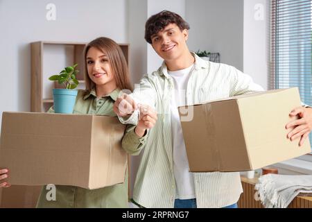 Jeune couple avec clés et boîtes de déménagement dans leur nouvel appartement Banque D'Images