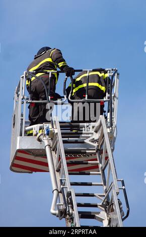 deux pompiers sur le dessus du camion de pompiers pendant les exercices d'incendie Banque D'Images