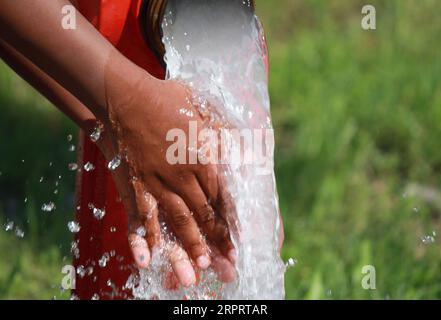 grosse bouche d'incendie rouge et l'eau rafraîchissante qui sort copieuse et les mains d'un enfant Banque D'Images