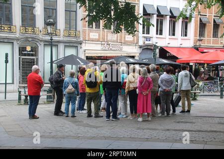 Une foule de touristes écoutent un guide touristique sur la Grand place de Bruxelles Banque D'Images