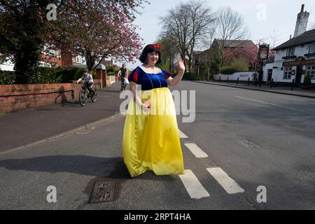 200411 -- STOCKPORT, 11 avril 2020 -- Rebecca Williamson, une fille vêtue de costumes blancs comme neige, encourage les gens au milieu de la pandémie de COVID-19 à Stockport, près de Manchester, en Grande-Bretagne, le 10 avril 2020. Rebecca, l'une de celles qui s'habillaient en bandes dessinées ou en personnages de contes de fées, a tenté de remonter le moral des gens dans le public pendant l'épidémie. Photo de /Xinhua UK-STOCKPORT-COVID-19-BLANC NEIGE JonxSuper PUBLICATIONxNOTxINxCHN Banque D'Images