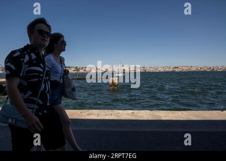 Almada, Portugal. 27 août 2023. Des gens vus marchant près de la rivière Tejo dans la ville d'Almada. Situé sur la rive sud du fleuve Tejo, Almada est le meilleur point de vue sur la ville de Lisbonne, avec le château, l'ascenseur panoramique de Boca do Vento et la statue du Christ Roi construite en 1959, ils sont utilisés comme points d'observation. (Photo Jorge Castellanos/SOPA Images/Sipa USA) crédit : SIPA USA/Alamy Live News Banque D'Images