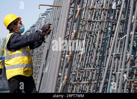 200412 -- ZHENGZHOU, le 12 avril 2020 -- Un ouvrier fouille des barres d'armature dans une zone de production de poutres qui fait partie du chantier de construction d'une ligne de chemin de fer à Zhengzhou, dans la province du Henan du centre de la Chine, le 12 avril 2020. Avec des mesures strictes contre la COVID-19 en place, la construction de la section Zhengzhou de la ligne ferroviaire de Zhengzhou à Jinan, province du Shandong dans l est de la Chine, a progressé de manière régulière. Le chemin de fer de 380 km est conçu pour fonctionner à la vitesse de 350 km/h. CHINE-ZHENGZHOU-CONSTRUCTION FERROVIAIRE À GRANDE VITESSE CN LIXAN PUBLICATIONXNOTXINXCHN Banque D'Images