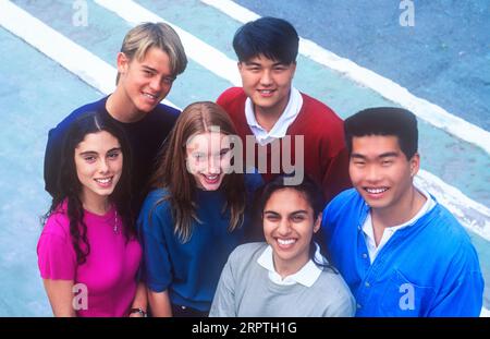 Élèves de l'école 15-17 ans groupe ethnique multiculturel de 6 heureux séduisant adolescent lycéen lycéen lycéens multiculturels dans des t-shirts colorés squash ensemble et pose à l'extérieur dans un environnement ensoleillé du campus universitaire. Étudiants adolescents hispaniques, coréens, asiatiques, orientaux Banque D'Images