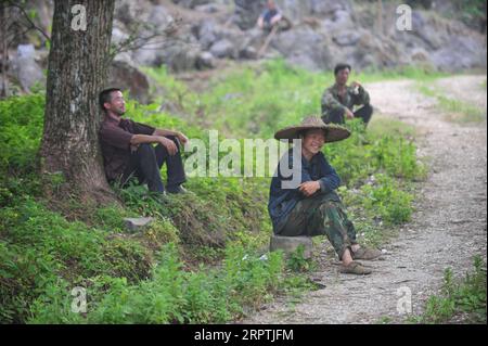 200416 -- RONGAN, le 16 avril 2020 -- le front de long Gexiong et les villageois se reposent après avoir planté des arbres dans le village de Tongbantun, dans le canton de Dongqi, dans le comté de Rongan, dans la région autonome de Guangxi Zhuang, dans le sud de la Chine, le 15 mai 2013. Long Gexiong, 52 ans, a quitté sa ville natale à 24 ans et est allé à la recherche d'emplois dans la ville de Liuzhou, dans la région autonome de Guangxi Zhuang, dans le sud de la Chine. Après deux décennies de travail à l'extérieur, il est enfin retourné dans son village natal dans les montagnes profondes. Longtemps abandonné l'école en 1986 en raison de la pauvreté et a gagné sa vie en plantant des pruniers. Cependant, les collines arides et la pénurie d'eau resu Banque D'Images