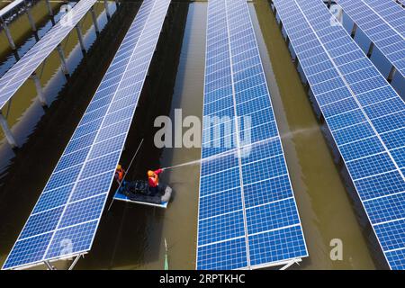 200416 -- CHANGXING, le 16 avril 2020 -- une photo aérienne prise le 16 avril 2020 montre des travailleurs sur un bateau inspectant le fonctionnement des panneaux photovoltaïques et nettoyant les modules photovoltaïques dans une ferme piscicole dans le village de Gulong du comté de Changxing, dans la province du Zhejiang de l'est de la Chine. La ferme piscicole, qui couvre une superficie de 500 mu environ 33,3 hectares, est utilisée pour élever du poisson et, en même temps, pour produire de l’électricité après l’installation de panneaux photovoltaïques à sa surface. Générant plus de 20 millions de kilowattheures d’électricité annuellement, l’application de panneaux photovoltaïques peut générer un chiffre d’affaires de plus de 10 millions Banque D'Images