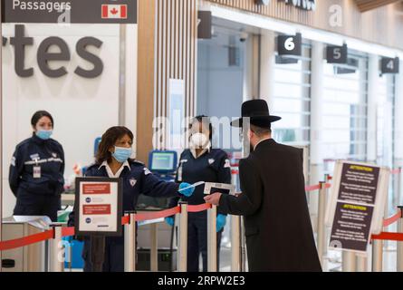 200420 -- TORONTO, le 20 avril 2020 -- Un agent de sécurité 2nd L remet un nouveau masque facial à un voyageur pendant l'épidémie de COVID-19 à l'aéroport international Pearson de Toronto, Canada, le 20 avril 2020. Le ministre canadien des Transports, Marc Garneau, a annoncé le 17 avril une nouvelle mesure qui entrera en vigueur le 20 avril, obligeant tous les passagers des compagnies aériennes à se couvrir la bouche et le nez avec un masque non médical ou un autre masque facial aux points de contrôle de l’aéroport. Photo de /Xinhua CANADA-TORONTO-COVID-19-MESURES ZouxZheng PUBLICATIONxNOTxINxCHN Banque D'Images