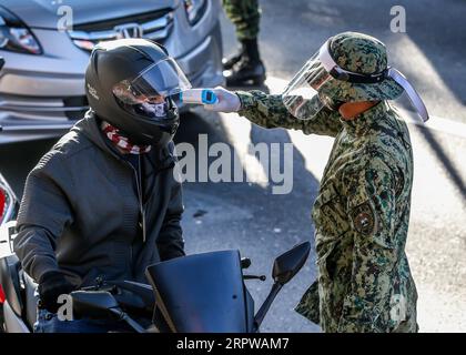 200424 -- MANILLE, le 24 avril 2020 Xinhua -- Un policier de la PNP de la police nationale philippine vérifie la température corporelle d'un automobiliste à un poste de contrôle à Manille, aux Philippines, le 24 avril 2020. Vendredi, le gouvernement philippin a annoncé qu’un confinement dans la région métropolitaine de Manille et les provinces de l’île principale de Luzon avec un grand nombre de nouvelles infections à coronavirus resterait en place jusqu’au 15 mai. Xinhua/Rouelle Umali PHILIPPINES-MANILA-COVID-19-LOCKDOWN PUBLICATIONxNOTxINxCHN Banque D'Images