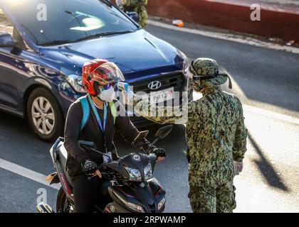 200424 -- MANILLE, le 24 avril 2020 Xinhua -- Un policier de la PNP de la police nationale philippine vérifie la température corporelle d'un automobiliste à un poste de contrôle à Manille, aux Philippines, le 24 avril 2020. Vendredi, le gouvernement philippin a annoncé qu’un confinement dans la région métropolitaine de Manille et les provinces de l’île principale de Luzon avec un grand nombre de nouvelles infections à coronavirus resterait en place jusqu’au 15 mai. Xinhua/Rouelle Umali PHILIPPINES-MANILA-COVID-19-LOCKDOWN PUBLICATIONxNOTxINxCHN Banque D'Images