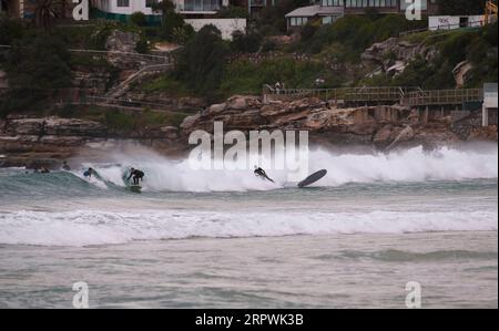 200428 -- SYDNEY, le 28 avril 2020 -- des surfeurs survolent une vague près de Bondi Beach à Sydney, en Australie, le 28 avril 2020. Des centaines d’Aussies ont afflué à l’eau mardi alors que l’emblématique plage de Bondi a rouvert pour les surfeurs et les nageurs après avoir été fermée en raison du COVID-19. AUSTRALIE-SYDNEY-COVID-19-PLAGE BaixXuefei PUBLICATIONxNOTxINxCHN Banque D'Images