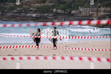 200428 -- SYDNEY, le 28 avril 2020 -- Surfers Walk à Bondi Beach à Sydney, Australie, le 28 avril 2020. Des centaines d’Aussies ont afflué à l’eau mardi alors que l’emblématique plage de Bondi a rouvert pour les surfeurs et les nageurs après avoir été fermée en raison du COVID-19. AUSTRALIE-SYDNEY-COVID-19-PLAGE BaixXuefei PUBLICATIONxNOTxINxCHN Banque D'Images