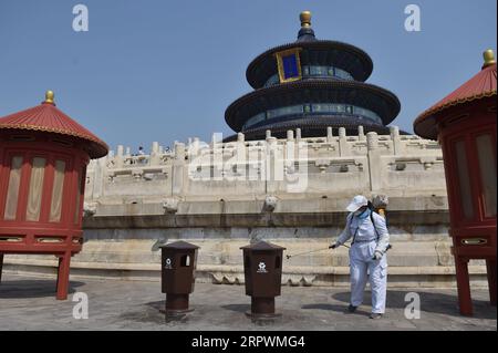 200429 -- BEIJING, le 29 avril 2020 -- un membre du personnel désinfecte une poubelle devant la salle de prière pour de bonnes récoltes au Temple du ciel à Beijing, capitale de la Chine, le 29 avril 2020. Le Temple du ciel, un site du patrimoine mondial de l’UNESCO temporairement fermé en raison de l’épidémie de COVID-19, a rouvert ses trois principaux groupes de bâtiments au public mercredi. Les terrains rouverts, à savoir la salle de prière pour la bonne récolte, la voûte impériale du ciel et l'autel circulaire, sont accessibles par un nombre limité de visiteurs via la réservation en ligne. CHINE-PÉKIN-COVID-19-TEMPLE DU CIEL-TOUR Banque D'Images