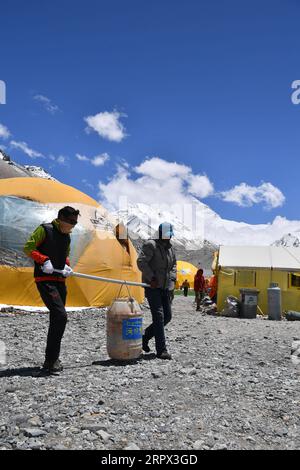 200505 -- CAMP DE BASE DU MONT QOMOLANGMA, le 5 mai 2020 -- des membres du personnel transportent les déchets de cuisine vers les installations d'élimination des déchets du camp de base du mont Qomolangma, dans la région autonome du Tibet du sud-ouest de la Chine, le 3 mai 2020. La Chine a lancé une nouvelle série de mesures sur la hauteur du mont Qomolangma, le plus haut sommet du monde. L’équipe de mesure est arrivée au camp de base il y a un mois, préparant la mesure prévue en mai. En tant que point de départ important et base arrière pour l'alpinisme, le camp de base du mont Qomolangma est équipé d'installations de vie de base et de fournitures médicales. Banque D'Images