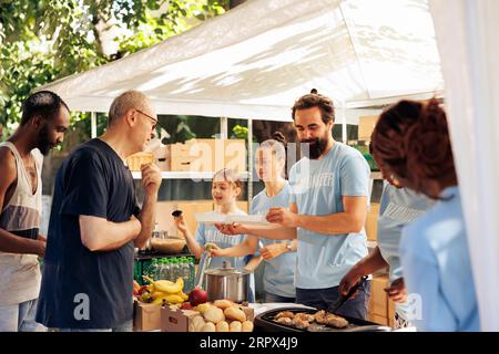Les membres de divers groupes caritatifs fournissent de l'aide et distribuent des dons alimentaires aux sans-abri et aux moins fortunés au refuge. Des bénévoles à Food Drive distribuent des repas chauds aux pauvres. Banque D'Images