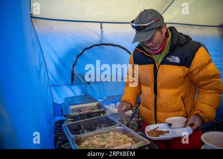 200513 -- MONT QOMOLANGMA, le 13 mai 2020 -- Un alpiniste a de la nourriture au camp avancé à une altitude de 6 500 mètres sur le mont Qomolangma, le 10 mai 2020. Pour faire face à la haute altitude et à la basse pression au camp avancé, les chefs utilisent des autocuiseurs pour préparer la nourriture. InTibet CHINE-TIBET-MONT QOMOLANGMA-ADVANCE CAMP-MEAL CN SunxFei PUBLICATIONxNOTxINxCHN Banque D'Images