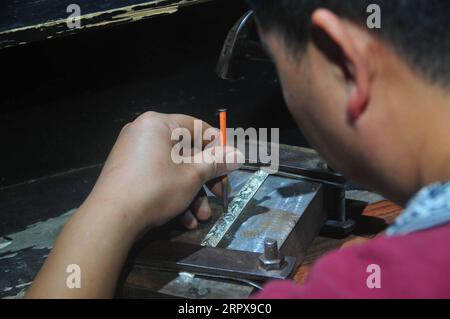 200514 -- FENGHUANG, le 14 mai 2020 -- Jiang Hua sculpte un ornement en argent dans un institut de formation de forgeage d'argent Miao dans le comté de Fenghuang, province du Hunan en Chine centrale, le 14 mai 2020. Le forgeage en argent du groupe ethnique Miao, inscrit au patrimoine culturel immatériel national, englobe plus de dix procédures. Jiang, 35 ans, est devenu orfèvre en 2006 et a commencé à apprendre la technique de forgeage d'argent Miao à l'institut de formation en 2015. À l'heure actuelle, Jiang gagne un revenu annuel de 80 000 yuans environ 11 276 dollars américains en faisant des ornements en argent avec la compétence qu'il a apprise. Banque D'Images