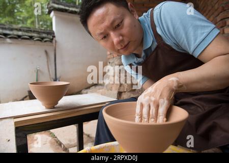 200517 -- HANGZHOU, le 17 mai 2020 -- Liu Jie travaille sur la réplique de Bakohan dans son atelier de Longquan, province du Zhejiang dans l'est de la Chine, le 7 mai 2020. Liu Jie, 35 ans et céramiste renommé à Longquan, a commencé à reproduire Bakohan depuis 2019. Il a jusqu'à présent réalisé plus de 500 répliques dans un effort pour approcher la perfection. Je souhaite reproduire sa beauté. A dit Liu. Bakohan est un bol à thé fabriqué à Longquan, en Chine, et offert au Japon pendant la dynastie des Song du Sud 1127-1279. Pendant l'ère de la dynastie Ming 1368-1644, Bakouhan a été trouvé pour avoir des fissures et a ensuite été envoyé en Chine pour être réparé. Le bol est maintenant disponible Banque D'Images