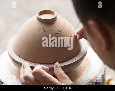 200517 -- HANGZHOU, le 17 mai 2020 -- Liu Jie travaille sur la réplique de Bakohan dans son atelier de Longquan, province du Zhejiang dans l'est de la Chine, le 7 mai 2020. Liu Jie, 35 ans et céramiste renommé à Longquan, a commencé à reproduire Bakohan depuis 2019. Il a jusqu'à présent réalisé plus de 500 répliques dans un effort pour approcher la perfection. Je souhaite reproduire sa beauté. A dit Liu. Bakohan est un bol à thé fabriqué à Longquan, en Chine, et offert au Japon pendant la dynastie des Song du Sud 1127-1279. Pendant l'ère de la dynastie Ming 1368-1644, Bakouhan a été trouvé pour avoir des fissures et a ensuite été envoyé en Chine pour être réparé. Le bol est maintenant disponible Banque D'Images