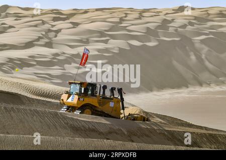 200518 -- YULI, le 18 mai 2020 -- Un ouvrier conduit un bulldozer sur le chantier de construction d'une autoroute dans le désert de Taklimakan, dans la région autonome ouïgoure du Xinjiang, au nord-ouest de la Chine, le 16 mai 2020. La construction de l'autoroute Yuli-Qiemo, la troisième route nord-sud traversant le désert de Taklimakan, est entrée dans la ruée finale. Les travailleurs de China Communications Construction Company Ltd. Travaillent sur la plus grande dune de ce projet, avec un volume estimé à 1,2 millions de mètres cubes de sable à traiter. Ils ont établi des camps à côté de la dune pour la commodité du travail, et reçoivent les nécessités quotidiennes sur Banque D'Images
