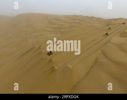 200518 -- YULI, le 18 mai 2020 -- des ouvriers conduisent des bulldozers sur le chantier de construction d'une autoroute dans le désert de Taklimakan, dans la région autonome ouïgoure du Xinjiang, au nord-ouest de la Chine, le 16 mai 2020. La construction de l'autoroute Yuli-Qiemo, la troisième route nord-sud traversant le désert de Taklimakan, est entrée dans la ruée finale. Les travailleurs de China Communications Construction Company Ltd. Travaillent sur la plus grande dune de ce projet, avec un volume estimé à 1,2 millions de mètres cubes de sable à traiter. Ils ont établi des camps à côté de la dune pour la commodité du travail, et reçoivent les nécessités quotidiennes sur un Banque D'Images