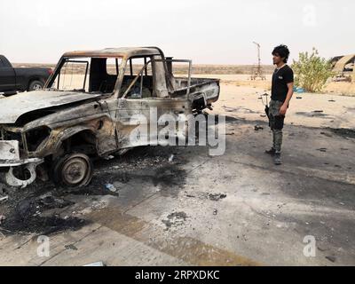 200518 -- TRIPOLI, le 18 mai 2020 Xinhua -- Un combattant du gouvernement soutenu par l'ONU se tient devant un véhicule détruit dans la base aérienne de Watya, à environ 140 km au Sud-Ouest de Tripoli, Libye, le 18 mai 2020. Le gouvernement libyen soutenu par l'ONU a annoncé lundi le rachat d'une base aérienne majeure de l'armée rivale basée à l'est dans le sud-ouest de la Libye. Photo de Hamza Turkia/Xinhua LIBYA-TRIPOLI-BASE AÉRIENNE-PRISE DE CONTRÔLE DE PUBLICATIONxNOTxINxCHN Banque D'Images