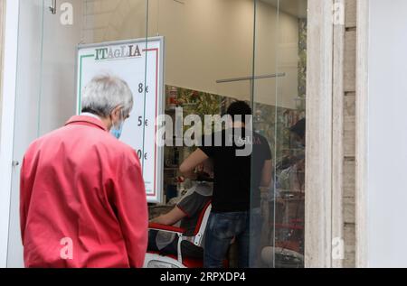 200518 -- ROME, le 18 mai 2020 -- Un homme attend de se faire couper les cheveux à Rome, Italie, le 18 mai 2020. Lundi, le troisième et plus grand assouplissement du confinement de dix semaines est entré en vigueur. Magasins, restaurants, bars, salons de coiffure, salons de beauté, les musées et les exploitants de bord de mer sont tous autorisés à rouvrir, à condition de respecter les règles de distanciation sociale entre le personnel et les membres du public et de désinfection des installations. Les Italiens sont également autorisés à se déplacer dans la région où ils vivent. ITALIE-ROME-COVID-19-ASSOUPLISSEMENT DU CONFINEMENT ChengxTingting PUBLICATIONxNOTxINxCHN Banque D'Images