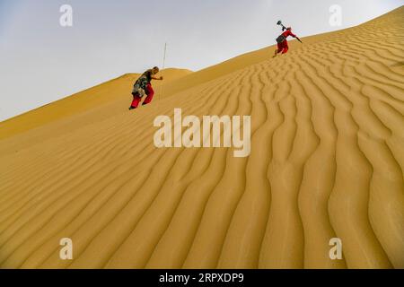 200519 -- PÉKIN, le 19 mai 2020 -- l'arpenteur Liu Yaojun R et son assistant Gan Caiyun marchent sur une dune sur le chantier de construction d'une autoroute dans le désert de Taklimakan, dans le nord-ouest de la Chine, dans la région autonome ouïgoure du Xinjiang, le 17 mai 2020. PHOTOS XINHUA DU JOUR HuxHuhu PUBLICATIONxNOTxINxCHN Banque D'Images