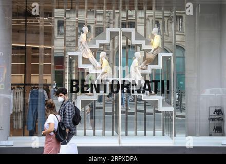 200518 -- ROME, le 18 mai 2020 -- les gens passent devant un magasin de vêtements avec le signe Bienvenue à Rome, Italie, le 18 mai 2020. Lundi, le troisième et plus grand assouplissement du confinement de dix semaines est entré en vigueur. Magasins, restaurants, bars, salons de coiffure, salons de beauté, les musées et les exploitants de bord de mer sont tous autorisés à rouvrir, à condition de respecter les règles de distanciation sociale entre le personnel et les membres du public et de désinfection des installations. Les Italiens sont également autorisés à se déplacer dans la région où ils vivent. ITALIE-ROME-COVID-19-ASSOUPLISSEMENT DU CONFINEMENT ChengxTingting PUBLICATIONxNOTxINxCHN Banque D'Images