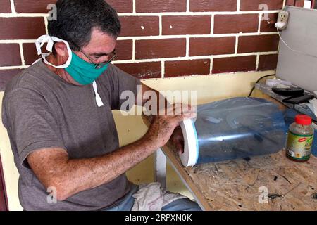 200529 -- LA HAVANE, le 29 mai 2020 Xinhua -- Ruben Ruiz, fils d'Iraida Hernandez, fabrique des écrans faciaux médicaux à partir de matériaux recyclés à la maison dans la banlieue de la Havane, Cuba, le 27 mai 2020. Iraida Hernandez, 87 ans, ne s'attendait pas à retourner à sa vieille machine à coudre dans son âge avancé, mais le besoin de protéger sa famille l'a mise à nouveau devant les rouleaux de fil et les coupes de tissu. La femme au foyer, qui vit à la périphérie de la Havane, fabrique des masques faciaux pour protéger ses proches et ses voisins du COVID-19. Hernandez n'est pas seul. Son fils, Ruben Ruiz, technicien en construction civile, fabrique également medi Banque D'Images