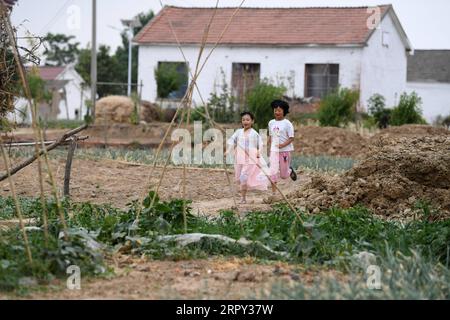 200612 -- HEFEI, le 12 juin 2020 -- Chu Siyang L traîne avec son camarade de classe dans le village de Wangli, dans le comté de Yingshang, province de l'Anhui, dans l'est de la Chine, le 9 juin 2020. CHU Siyang est une jeune fille de 9 ans dont les parents sont tous deux des travailleurs de la base engagés dans la lutte pour l'éradication de la pauvreté dans le pays. En 2017, Zheng Jiawei, père de Siyang, s'est porté volontaire pour travailler comme travailleur de base dans le village de Wangli, dans le comté de Yingshang, aidant les villageois locaux à se débarrasser de la pauvreté et à développer les infrastructures. Sa mère, déjà occupée à travailler en première ligne dans les villages frappés par la pauvreté, ne pouvait pas perdre de temps pour s’occuper de Siya Banque D'Images