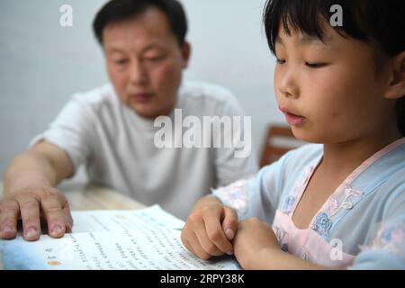 200612 -- HEFEI, 12 juin 2020 -- Zheng Jiawei aide sa fille Chu Siyang à faire ses études dans le village de Wangli, dans le comté de Yingshang, dans la province de l'Anhui, dans l'est de la Chine, le 9 juin 2020. CHU Siyang est une jeune fille de 9 ans dont les parents sont tous deux des travailleurs de la base engagés dans la lutte pour l'éradication de la pauvreté dans le pays. En 2017, Zheng Jiawei, père de Siyang, s'est porté volontaire pour travailler comme travailleur de base dans le village de Wangli, dans le comté de Yingshang, aidant les villageois locaux à se débarrasser de la pauvreté et à développer les infrastructures. Sa mère, déjà occupée à travailler en première ligne dans les villages touchés par la pauvreté, ne pouvait pas perdre de temps Banque D'Images