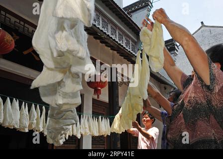 200613 -- HUZHOU, 13 juin 2020 -- Wang Yishi 1st L et les villageois sèchent des matériaux en soie pour la confection de courtepointes de soie à son musée de soie JILI dans la ville de Huzhou, province de Zhejiang dans l'est de la Chine, 12 juin 2020. La soie JILI, produite dans le village JILI de Huzhou, est célèbre pour sa haute qualité. Il a été désigné comme matériau pour fabriquer des cordes pour les empereurs chinois depuis le milieu de la dynastie Ming 1368-1644. En 2011, la technique de fabrication de la soie a été répertoriée comme l'un des patrimoines culturels immatériels nationaux. Il est connu dans le monde entier depuis 1851, lorsque la soie JILI a remporté le premier prix d'or pour la Chine lors de l'exposition mondiale Banque D'Images