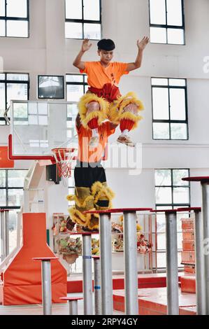 200614 -- TENGXIAN, 14 juin 2020 -- Qiu Haiwei front et Huang Qingliang pratiquent une routine de danse du lion dans l'école professionnelle secondaire de Tengxian, dans le comté de Tengxian, dans la région autonome de Guangxi Zhuang, dans le sud de la Chine, le 10 juin 2020. Remuant la tête et la queue, peaufinant les oreilles et grattant les joues -- les artistes dans un costume de lion doré ont bondi d'un pilier à l'autre et ont ensuite cavoré sur le sol aux clous des cymbales, des gongs et des battements de tambour pendant qu'ils pratiquaient un ensemble de mouvements de danse dans le comté de Tengxian. Quand ils ont terminé, deux jeunes hommes ont retiré le costume - Qiu Haiwei, 17 ans, avait joué comme le lion h. Banque D'Images