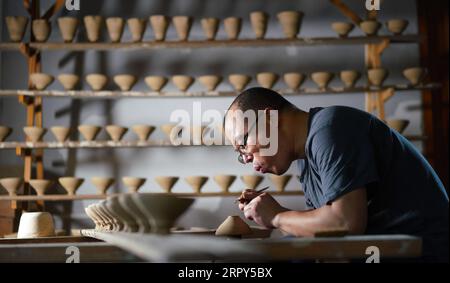 200615 -- NANCHANG, le 15 juin 2020 -- l'artisan Wu Yingshan fabrique une coupe de feuilles dans son atelier du comté de Ji an, province du Jiangxi dans l'est de la Chine, le 10 juin 2020. Il n'y a pas deux coupes de feuilles identiques, tout comme il n'y a pas deux feuilles identiques dans le monde. La fabrication d'une coupe de feuille, un artisanat traditionnel endémique dans le comté de Ji an d'aujourd'hui, est spéciale - l'artisan doit intégrer une feuille dans la porcelaine sur laquelle il travaille. Wu Yingshan, un héritier des techniques de fabrication de coupe de feuilles, a commencé à étudier la porcelaine en 2003. Avec le développement de la production en vrac, les façons traditionnelles de fabriquer des coupes de feuilles sont Banque D'Images