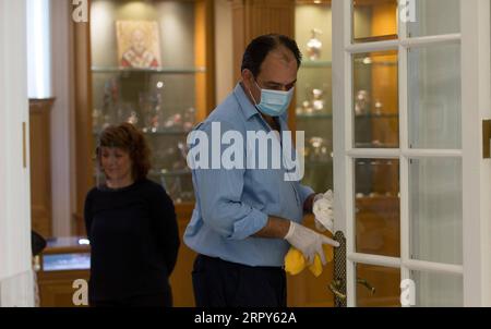 200616 -- ATHÈNES, le 16 juin 2020 -- Un membre du personnel portant un masque facial nettoie une porte au Musée Benaki à Athènes, en Grèce. Le 15 juin 2020. Les musées de toute la Grèce ont rouvert lundi après une fermeture de trois mois, tandis que les sites archéologiques avaient ouvert leurs portes en mai. GRÈCE-ATHÈNES-MUSEUMS-ROUVRIR MariosxLolos PUBLICATIONxNOTxINxCHN Banque D'Images